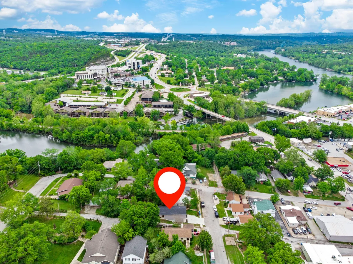 A tranquil exterior view of the river flanked by lush trees and nearby buildings, with visible roadways that hint at easy access to further attractions. The setting sun creates a peaceful yet adventurous mood, perfect for lakeside walks, fishing, or family outings.