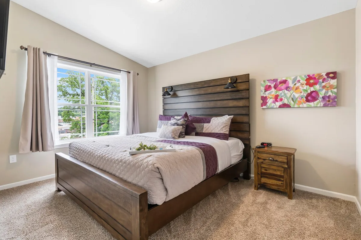A soothing bedroom with a wooden headboard, floral artwork, a window letting in natural light, and a nightstand. The calm, comfortable mood highlights the restful sleep experience described in the text.