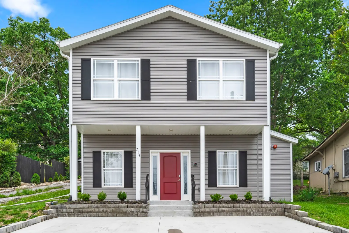 A crisp exterior photo showing the bright red front door, symmetrical windows, and white columns, projecting an inviting, festive vibe. The scene connects to the excitement of coming home after a group adventure downtown.