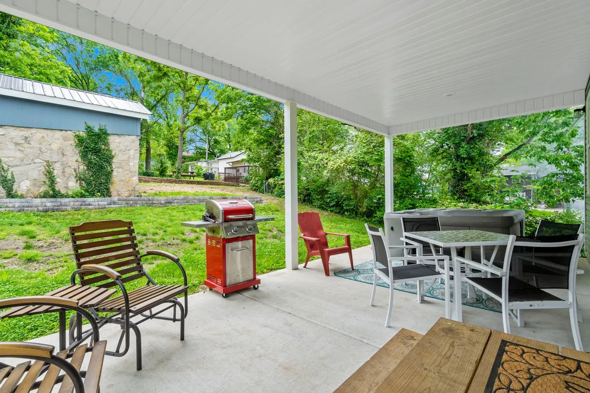 This image offers a complementary perspective on the outdoor living space, emphasizing the grill, comfortable seating area, and surrounding greenery. The mood is casual, with people enjoying sunset cookouts, morning coffee, and evening conversations under the stars.