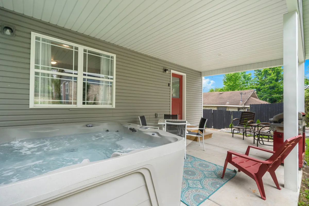 Here, the focus is on a welcoming outdoor area featuring a hot tub, cushioned seating, and a distinctive red door. The setting is ideal for sunset views, evening get-togethers, and celebrating special occasions outdoors, with an inviting and sociable mood.