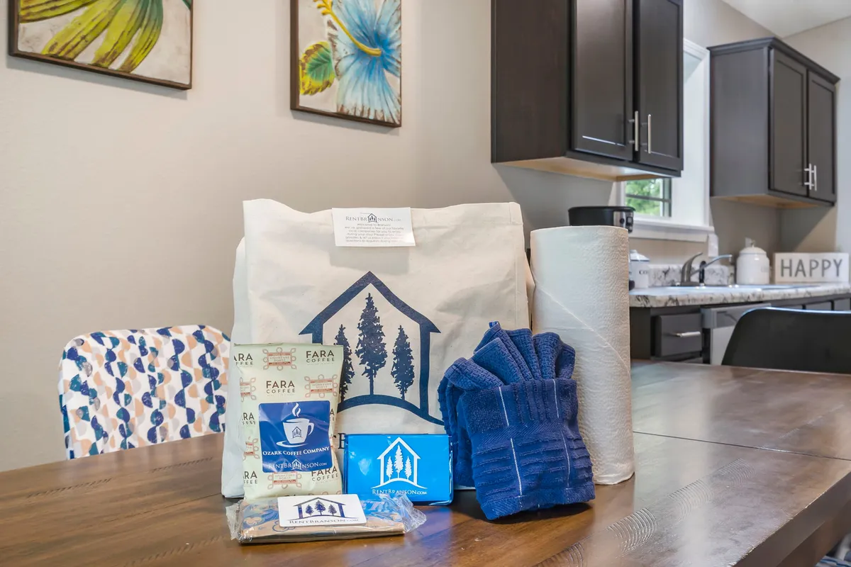 A cozy kitchen scene featuring a decorative welcome bag, packaged goods, colorful chairs, blue towels, and kitchen items. The setting hints at group meals, unpacking together, and shared moments that build memories.